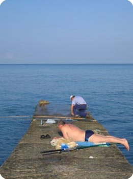 Mann in Badehose liegt auf Steg aus Beton